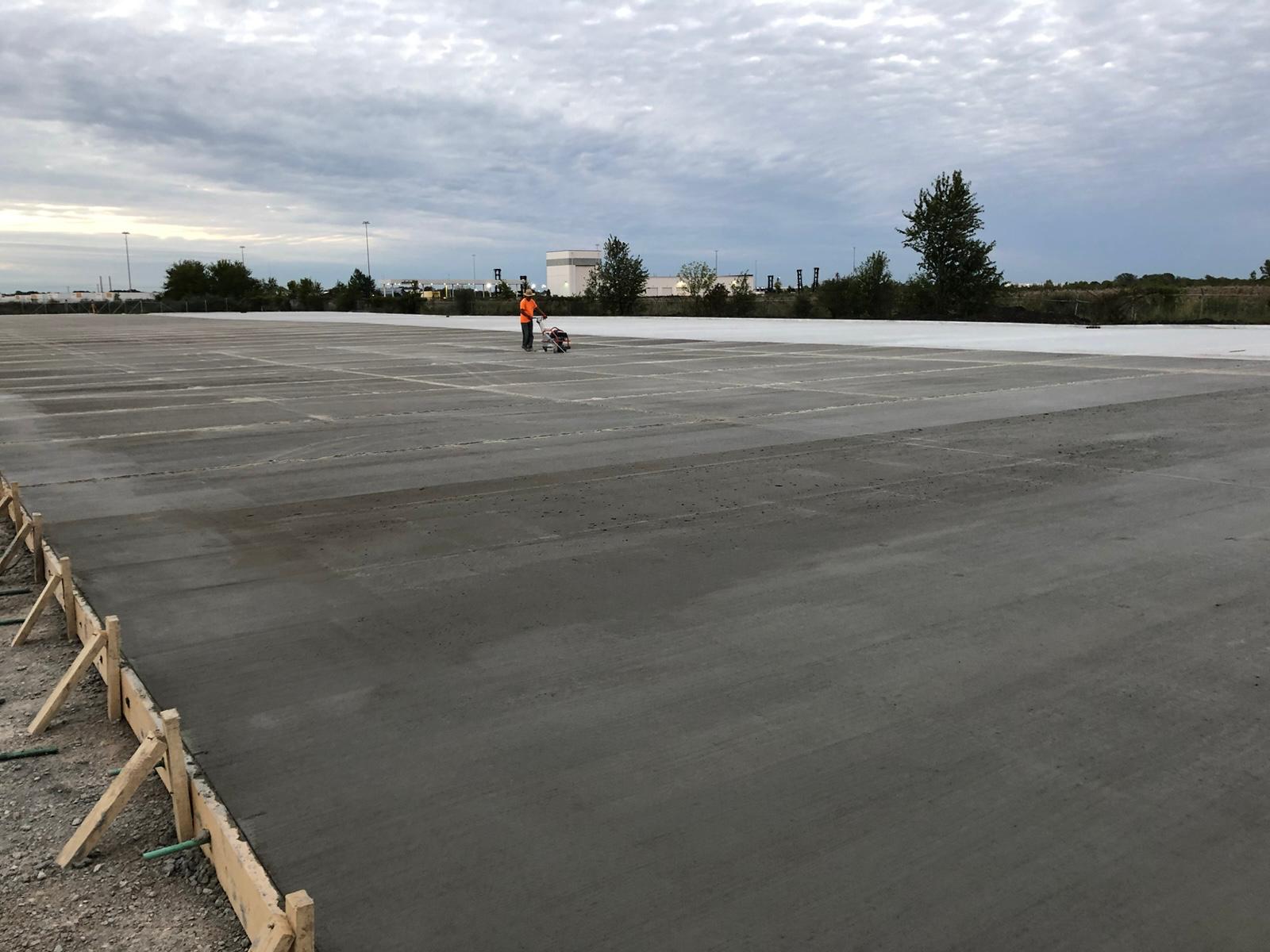 Freshly finished commercial concrete slab with forms and curing compound